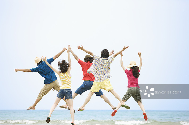在海滩上跳跃的男士和女士的后视图图片素材