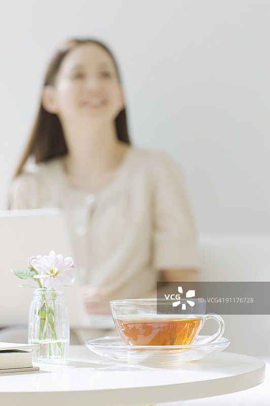 女人坐在沙发上使用笔记本电脑，焦点在前台图片素材
