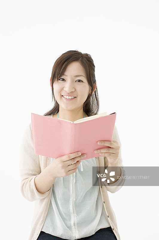 女人手持打开的书本，影棚拍摄图片素材