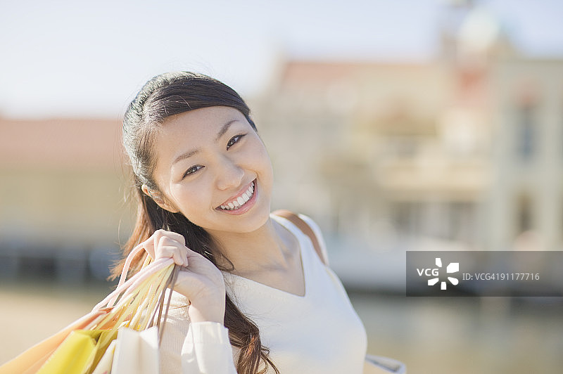 女人拿着购物袋，面带微笑图片素材