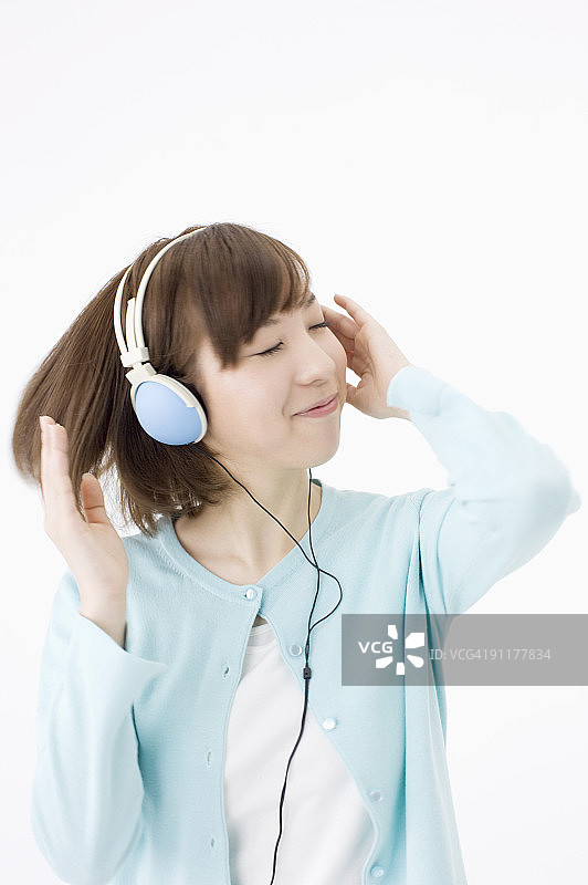 戴着耳机听音乐的年轻女人，工作室拍摄图片素材