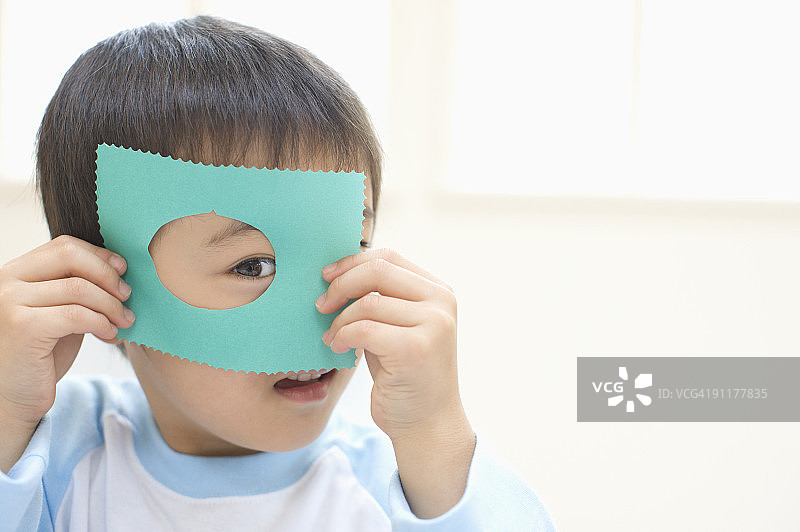 男孩正透过毛毡板上的洞往外看图片素材