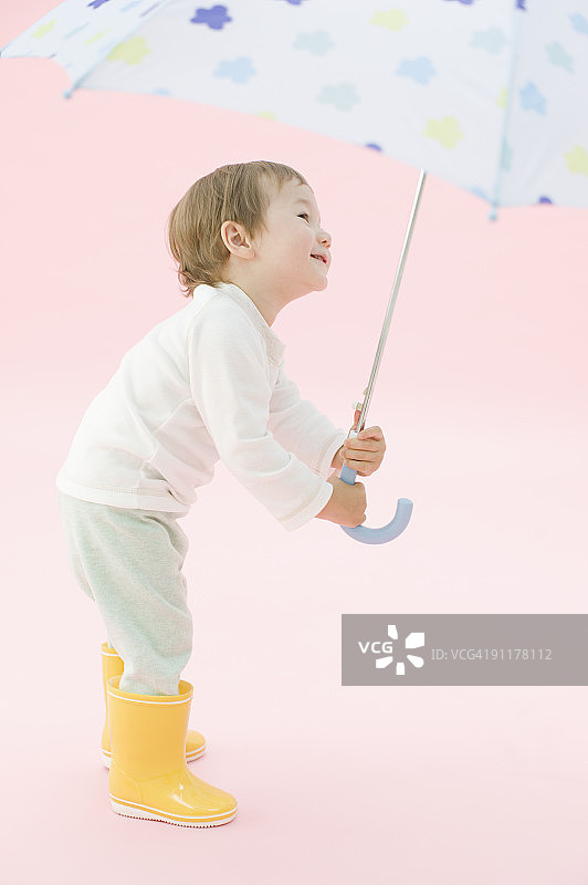 男孩穿雨靴打伞的影棚照片图片素材