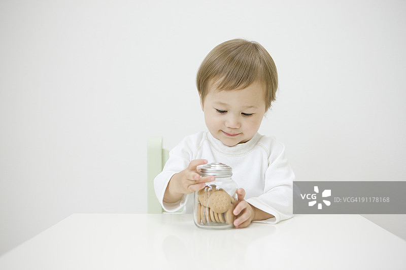 男孩试图打开装有饼干的罐子图片素材