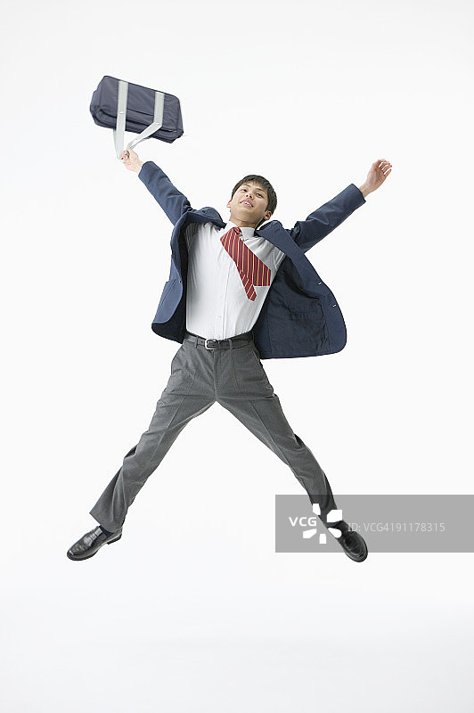 手提书包跳跃的高中生（影棚拍摄）图片素材