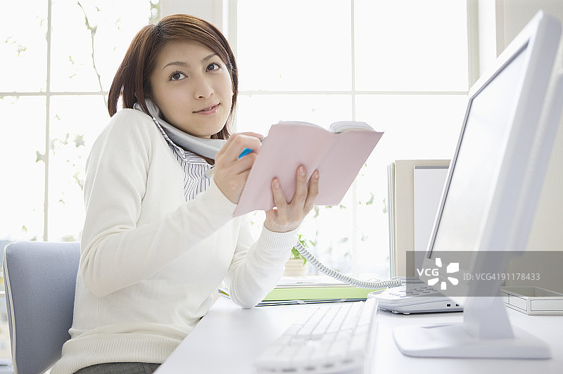 女人拿着日程本打电话图片素材
