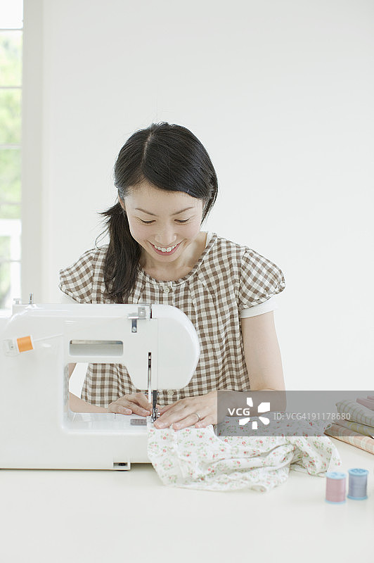女人使用缝纫机，面带微笑图片素材