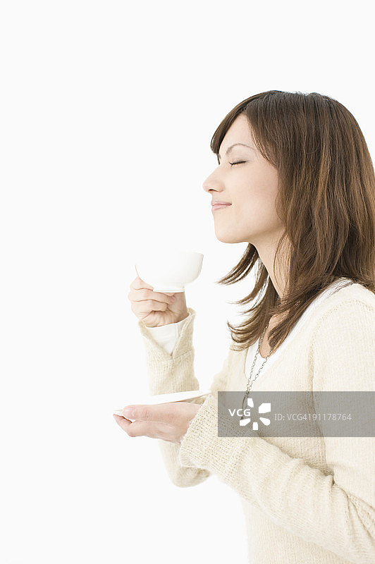 年轻女性喝茶，闭着眼睛，侧面视角图片素材