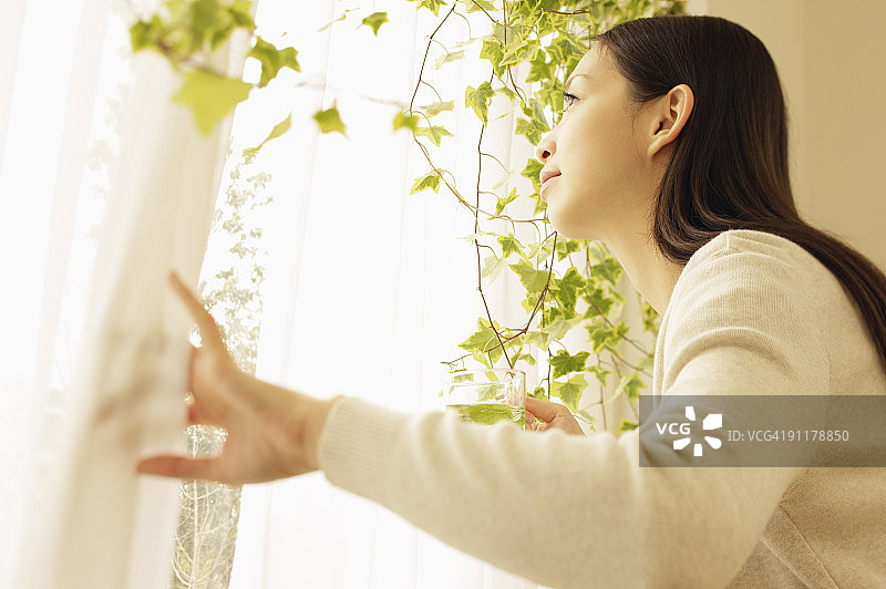 女人拉开窗帘，看向窗外，侧视图图片素材