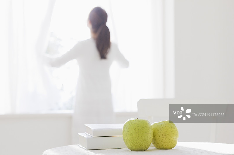女人打开窗帘，后视图，焦点在前图片素材