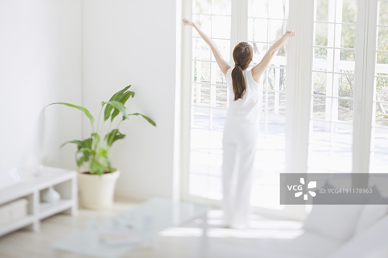 在窗边伸展双臂的女人背影图片素材