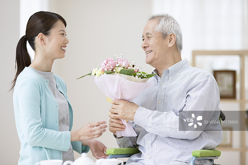 护理人员给坐轮椅的老年男子送花图片素材