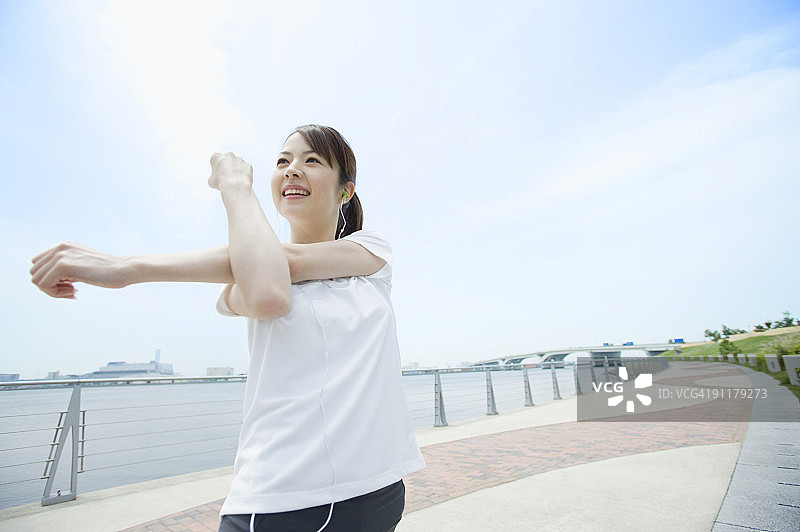 年轻女子戴着耳机做拉伸图片素材