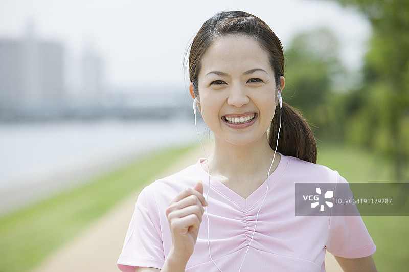 戴着耳机微笑慢跑的年轻女子图片素材