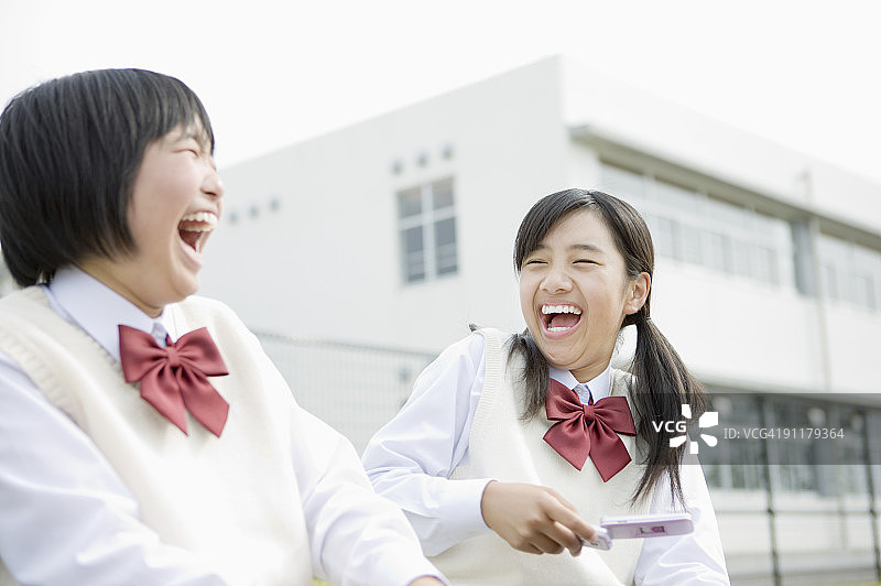 微笑着使用手机的女学生图片素材