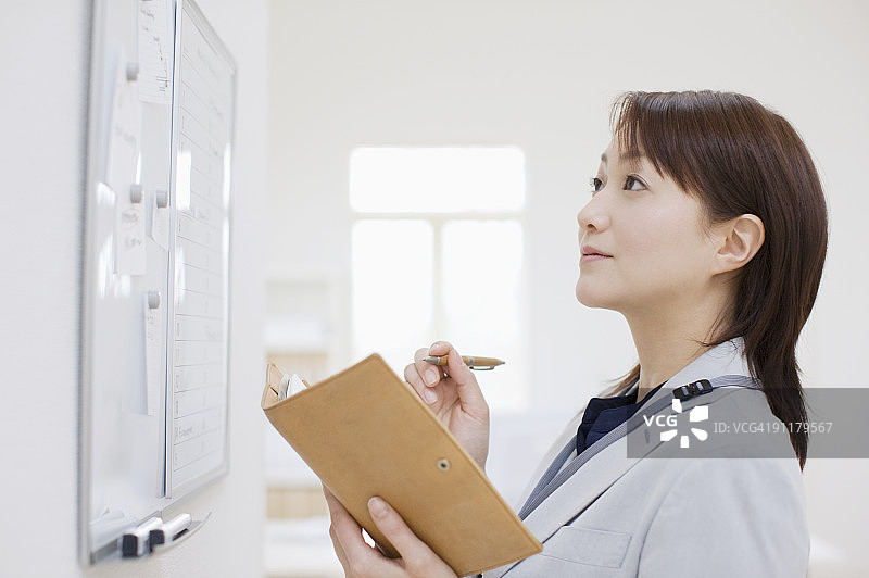 女商人在日程表前做笔记图片素材