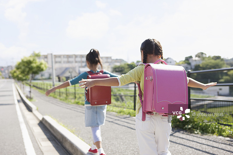 背着书包走在路边平衡的女孩（后视图）图片素材
