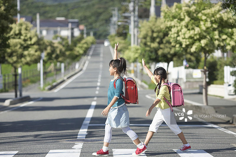 女孩们穿过马路，举起手，侧视图图片素材