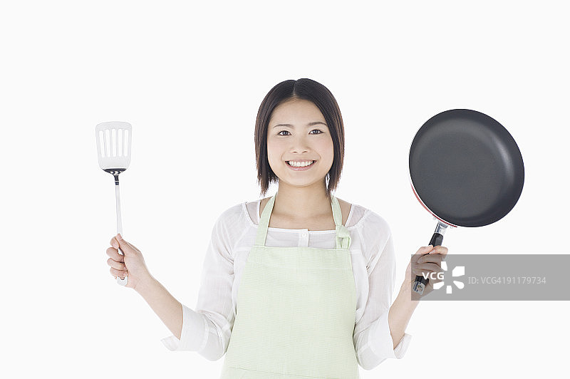 年轻女人拿着铲子和平底锅的影棚照图片素材