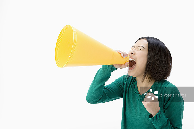 年轻女人对着扩音器喊叫，工作室拍摄图片素材