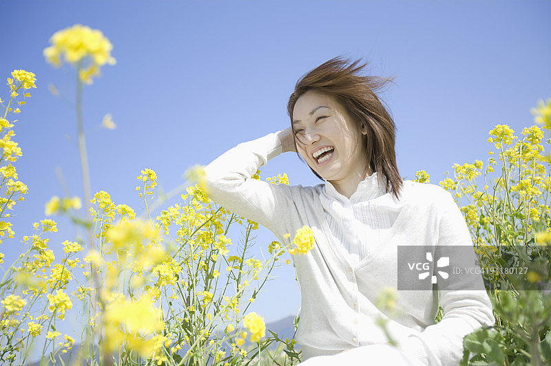 在油菜籽田中微笑的年轻女人图片素材