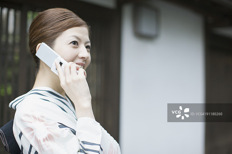 穿和服的女人在用手机，面带微笑图片素材