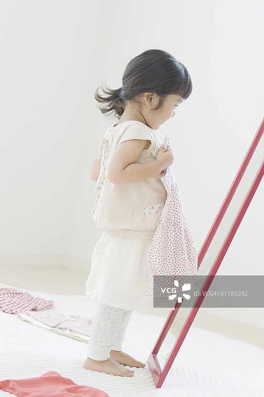 少女手拿连衣裙照镜子图片素材
