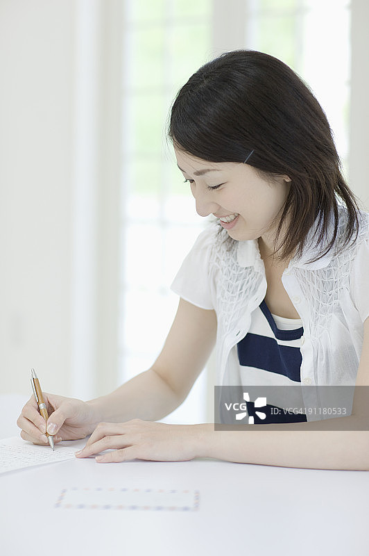 年轻女人写信，面带微笑图片素材