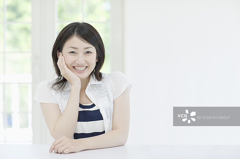 年轻女人微笑，手托着下巴图片素材