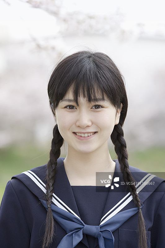 穿着校服，在樱桃树旁微笑的少女图片素材