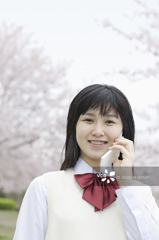 穿着校服微笑，用手机交谈的少女图片素材