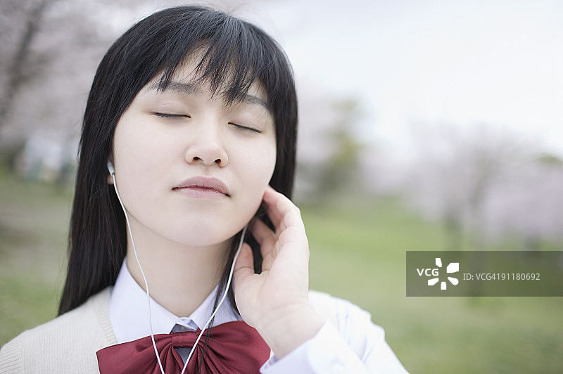 穿校服的青少年女孩闭着眼睛听音乐图片素材