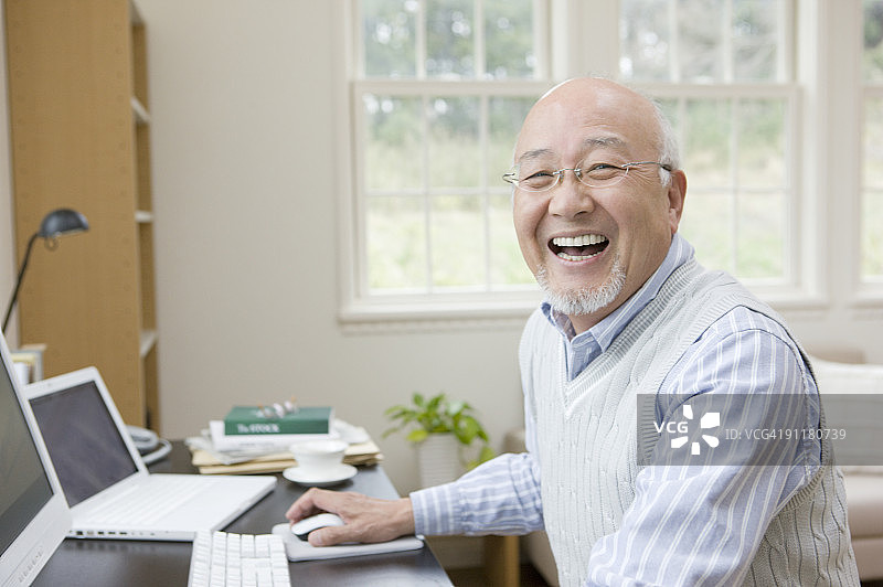 年长的男人在办公桌前微笑图片素材