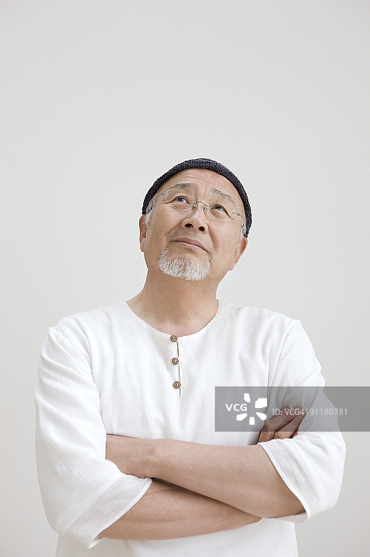 年长的男人抬头，双手交叉的特写肖像图片素材