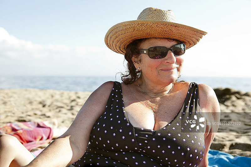 戴着帽子和眼镜在沙滩上的女人图片素材