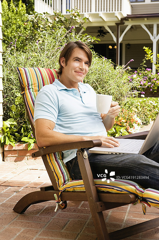 手拿咖啡杯和笔记本电脑的微笑男人图片素材