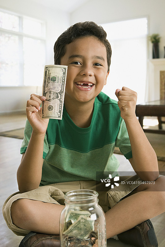 混血男孩拿着五美元钞票图片素材