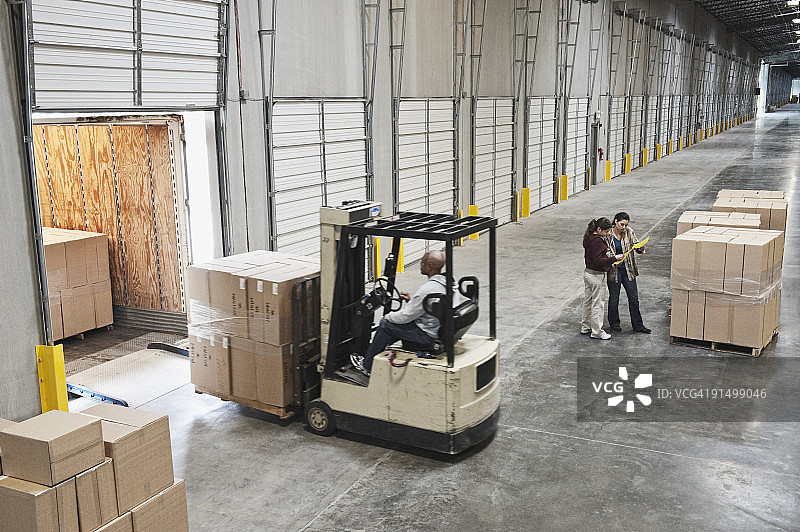 叉车在仓库装卸站将箱子搬到卡车上图片素材