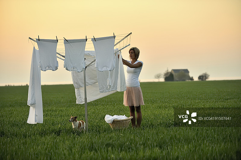 年轻女人日出时在田野洗衣服图片素材