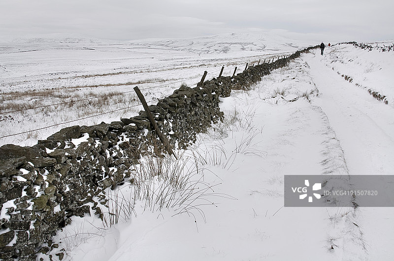 行人穿越白雪皑皑的冬季荒原图片素材