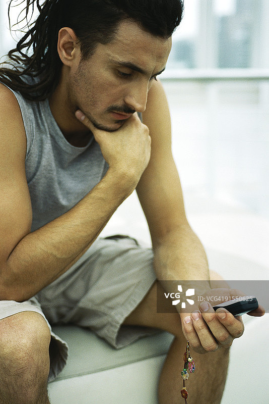 男人手托着下巴，看着手机图片素材