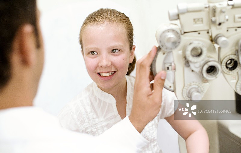 验光师使用屈光度计检查女孩的眼睛（10-11岁）图片素材