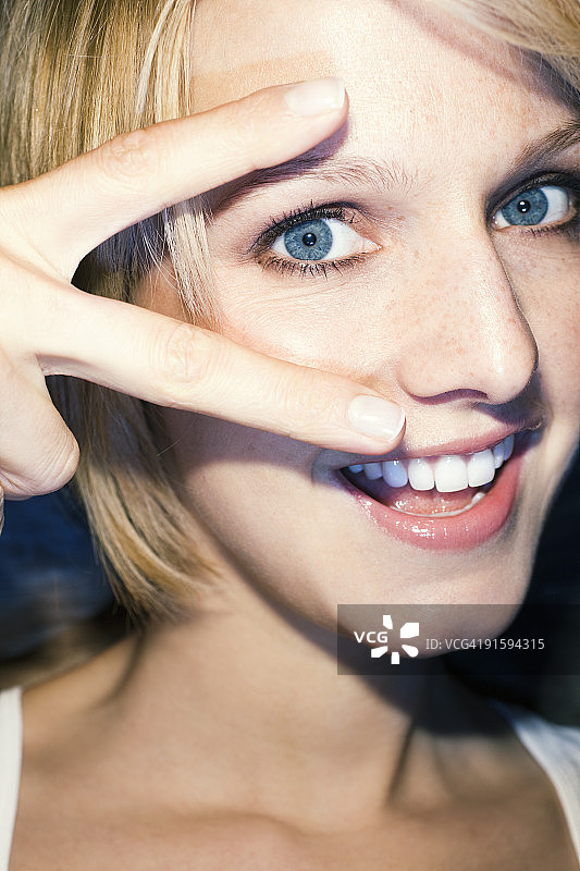 年轻女人做出和平手势，笑着，特写图片素材