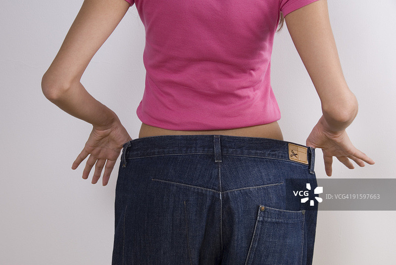 穿着肥大牛仔裤的女人，节食图片素材
