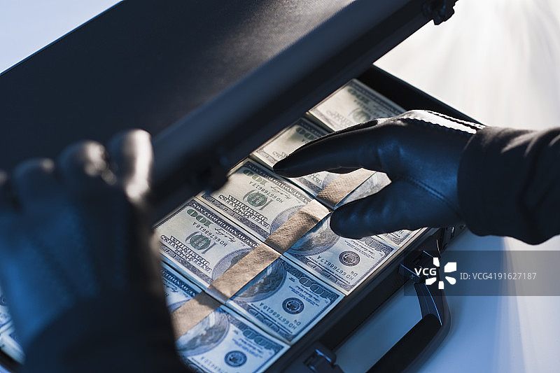 戴手套的手提着装满钱的公文包图片素材