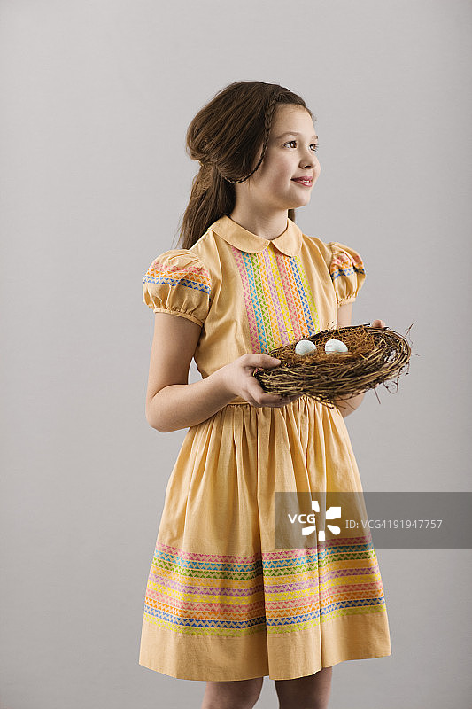 灰色背景下微笑的年轻女子拿着篮子的画像图片素材