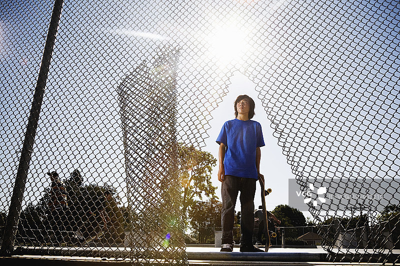 站在铁丝网围栏上的男孩的后视图图片素材