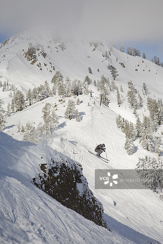 滑雪者从悬崖跳入新雪中图片素材