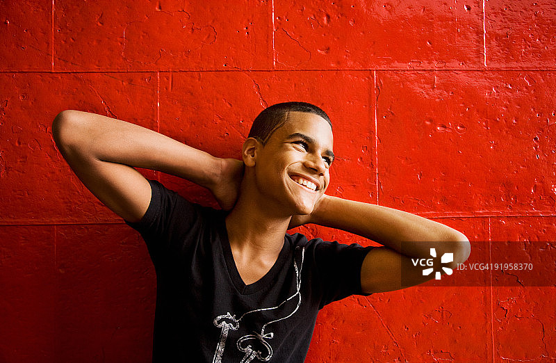 在红墙前放松的青少年男孩图片素材