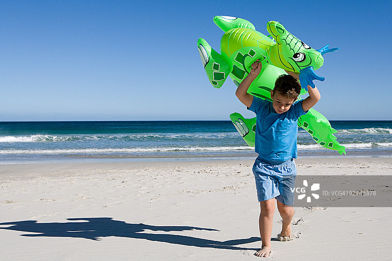 小男孩在海滩上 carrying 充气龙图片素材